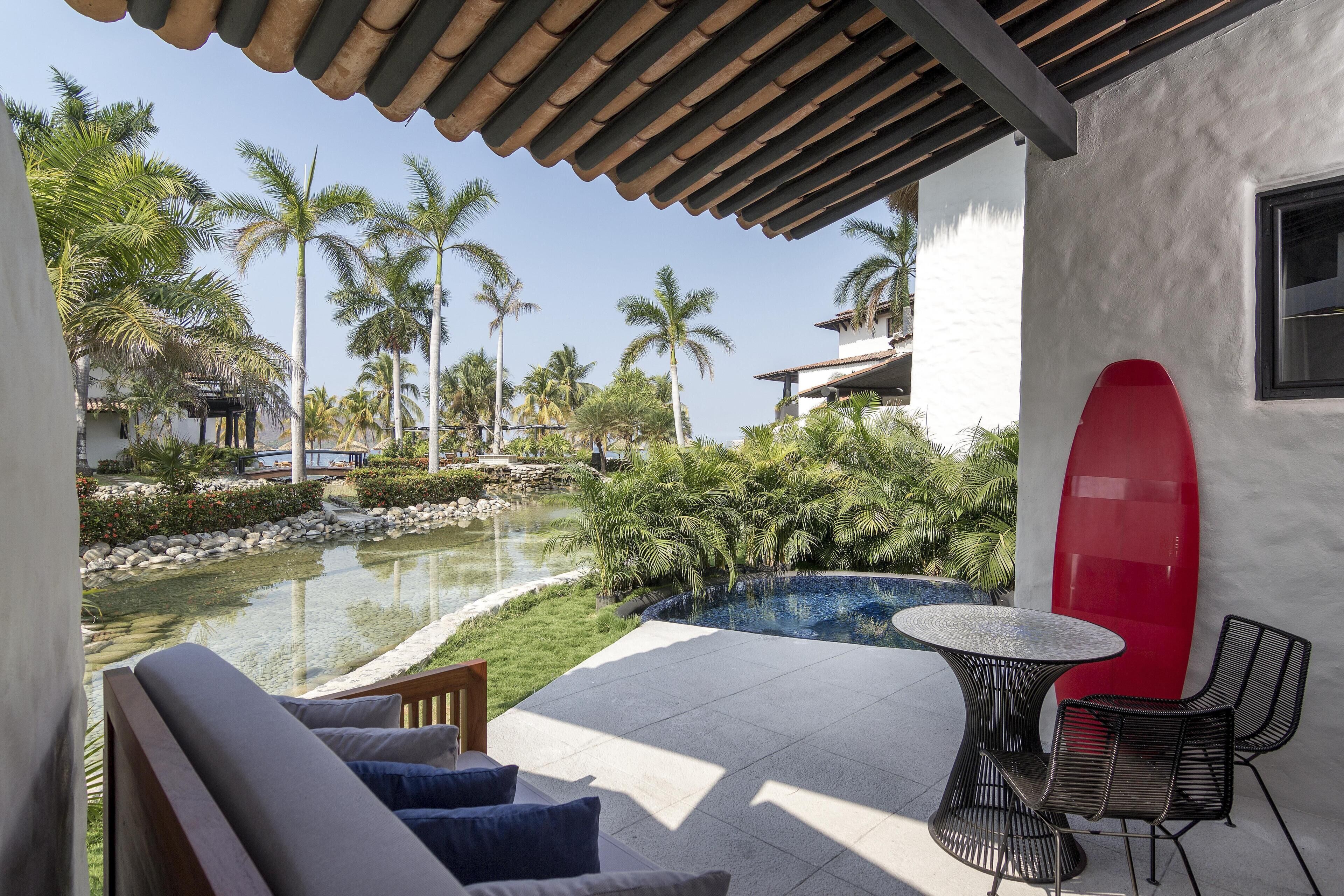 A poolside area with a red surfboard, a round table, and chairs.
