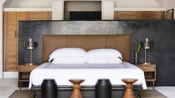 A modern bedroom with a large bed, wooden headboard, two bedside tables with lamps, and a dark accent wall.