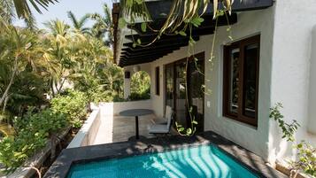 A swimming pool with a pergola, surrounded by lush greenery and a white building with large windows.