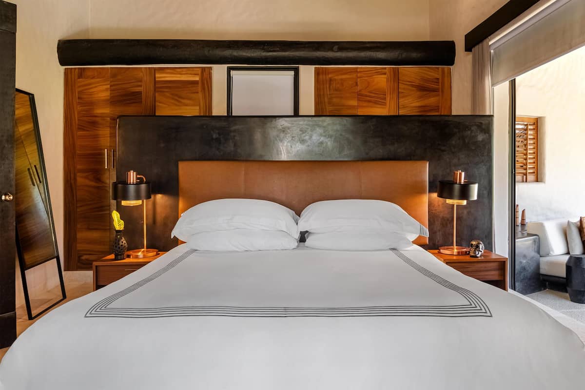 A bedroom with a large bed, wooden headboard, bedside lamps, and a nightstand.