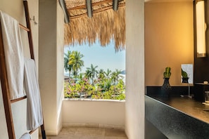 Un baño con vistas a palmeras y flores, un perchero, un lavabo y una planta en maceta.