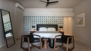Un dormitorio con cama, ventilador de techo, mesita de noche, espejo y pared con estampado geométrico.