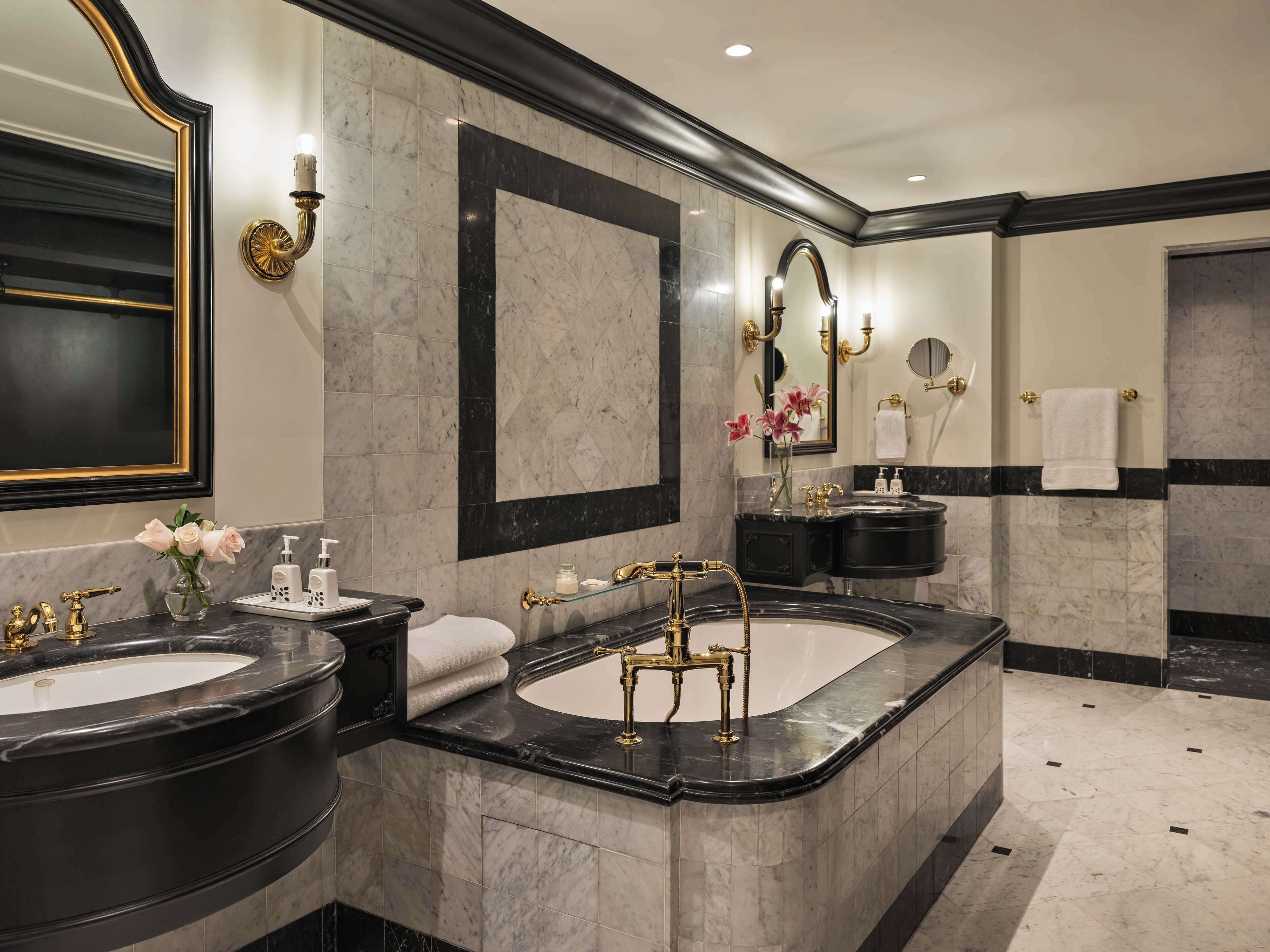 A luxurious bathroom with two sinks, a large mirror, and a vanity with a black countertop.