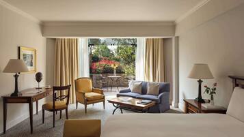 A hotel room with a bed, a sofa, a chair, a small table, a desk, and a view of the outdoors.