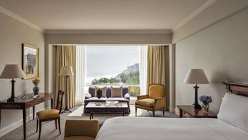 Une chambre d’hôtel avec un lit, un canapé, une chaise, un bureau et une vue sur la ville.