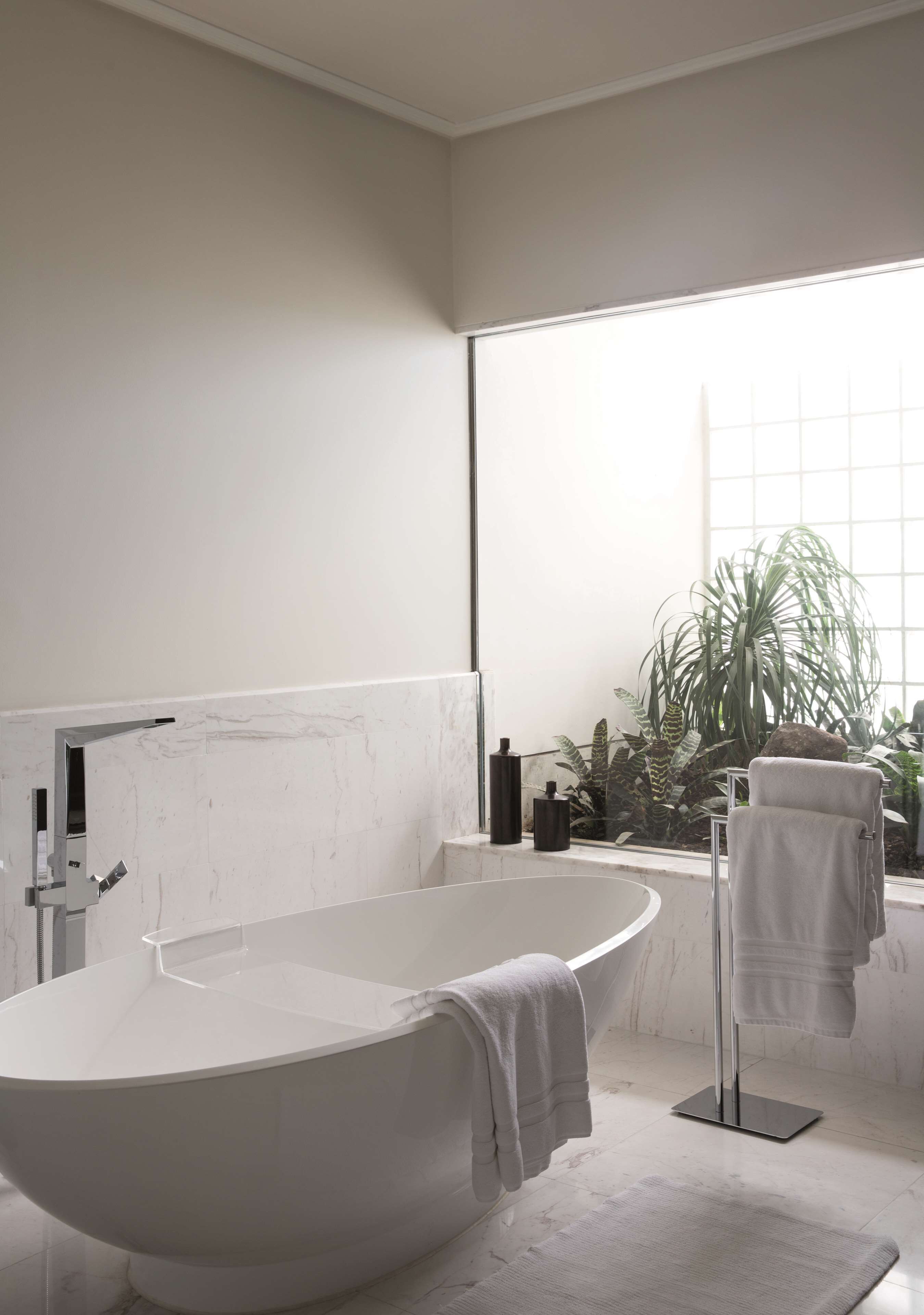 Un bagno moderno con una vasca freestanding, un appendi-asciugamani e una pianta in vaso.