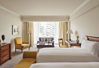 A hotel room with a large bed, a sofa, a desk, a chair, and a dresser.