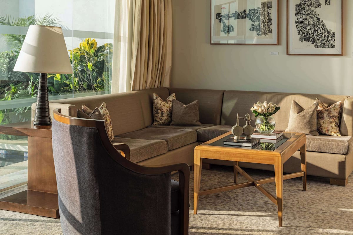 A modern living room with a sofa, armchair, coffee table, and artwork on the wall.