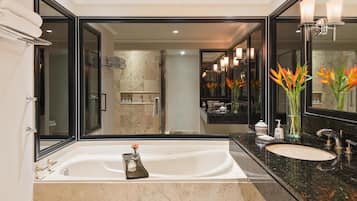 A modern bathroom with a large mirror, a bathtub, a sink, and a shower area.