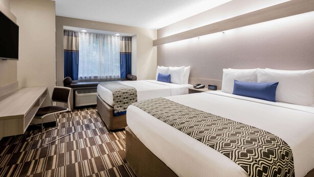 A hotel room with two beds, a desk, a chair, and a TV. - Microtel Inn & Suites by Wyndham Atlanta/Buckhead Area (Atlanta)