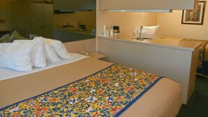 Habitación de hotel con cama, un pequeño escritorio con lavamanos y un espejo.