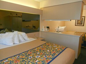 A hotel room with a bed, a small desk with a sink, and a mirror. - Americas Best Value Inn And Suites Mcdonough (McDonough)