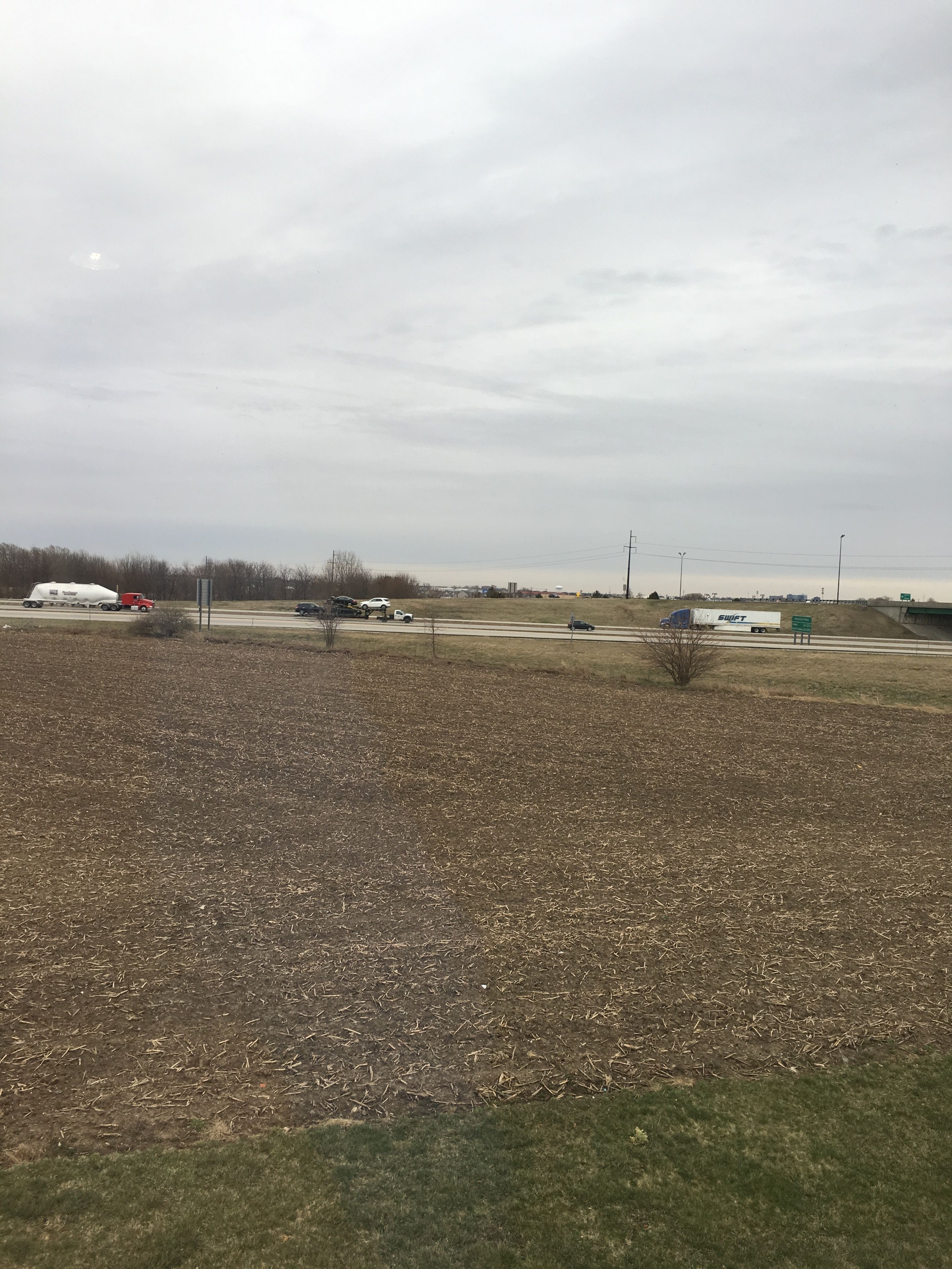 A wide, open field with a highway in the background.