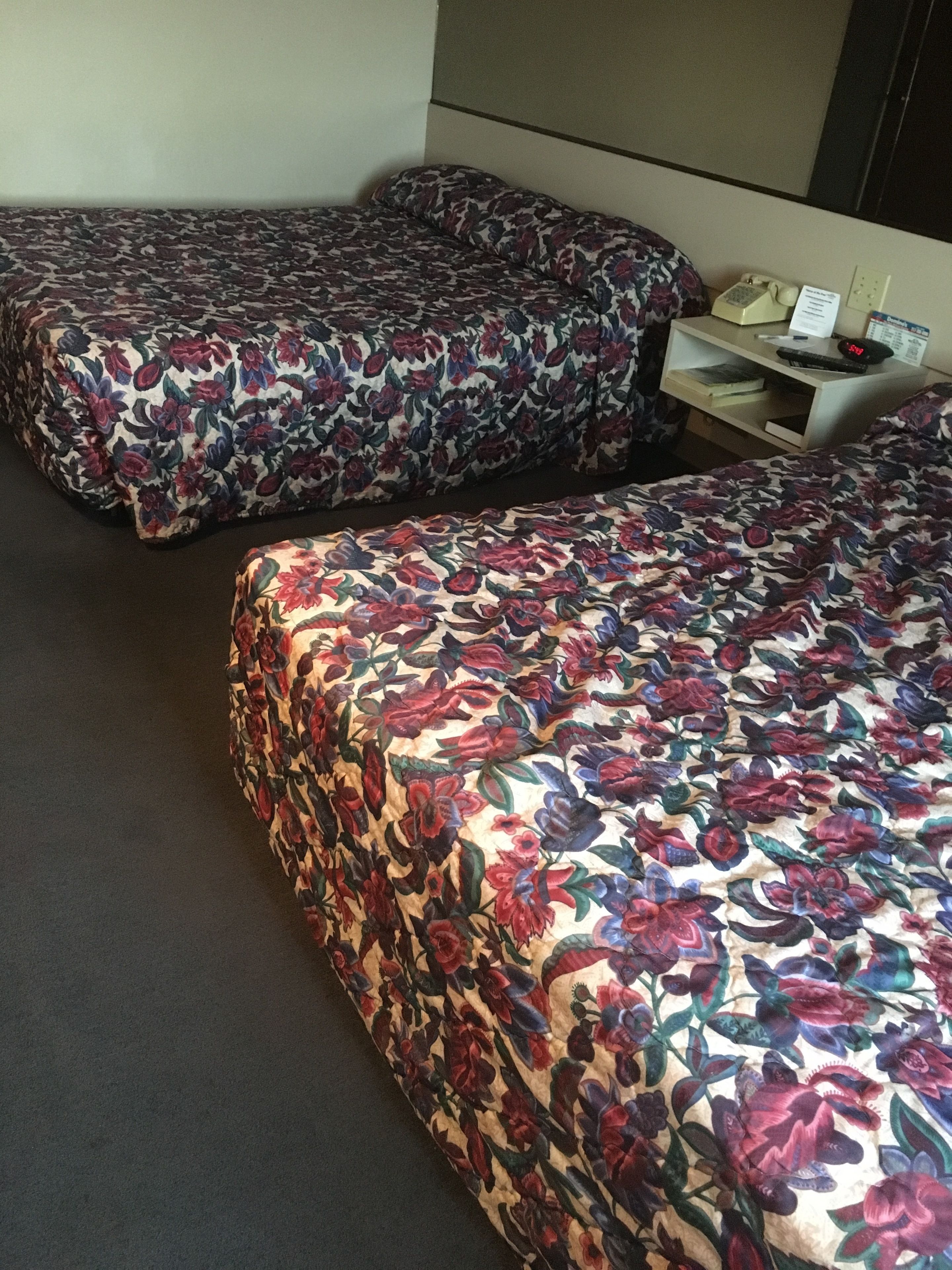 Zwei Einzelbetten mit floralem Bettbezug in einem Hotelzimmer.