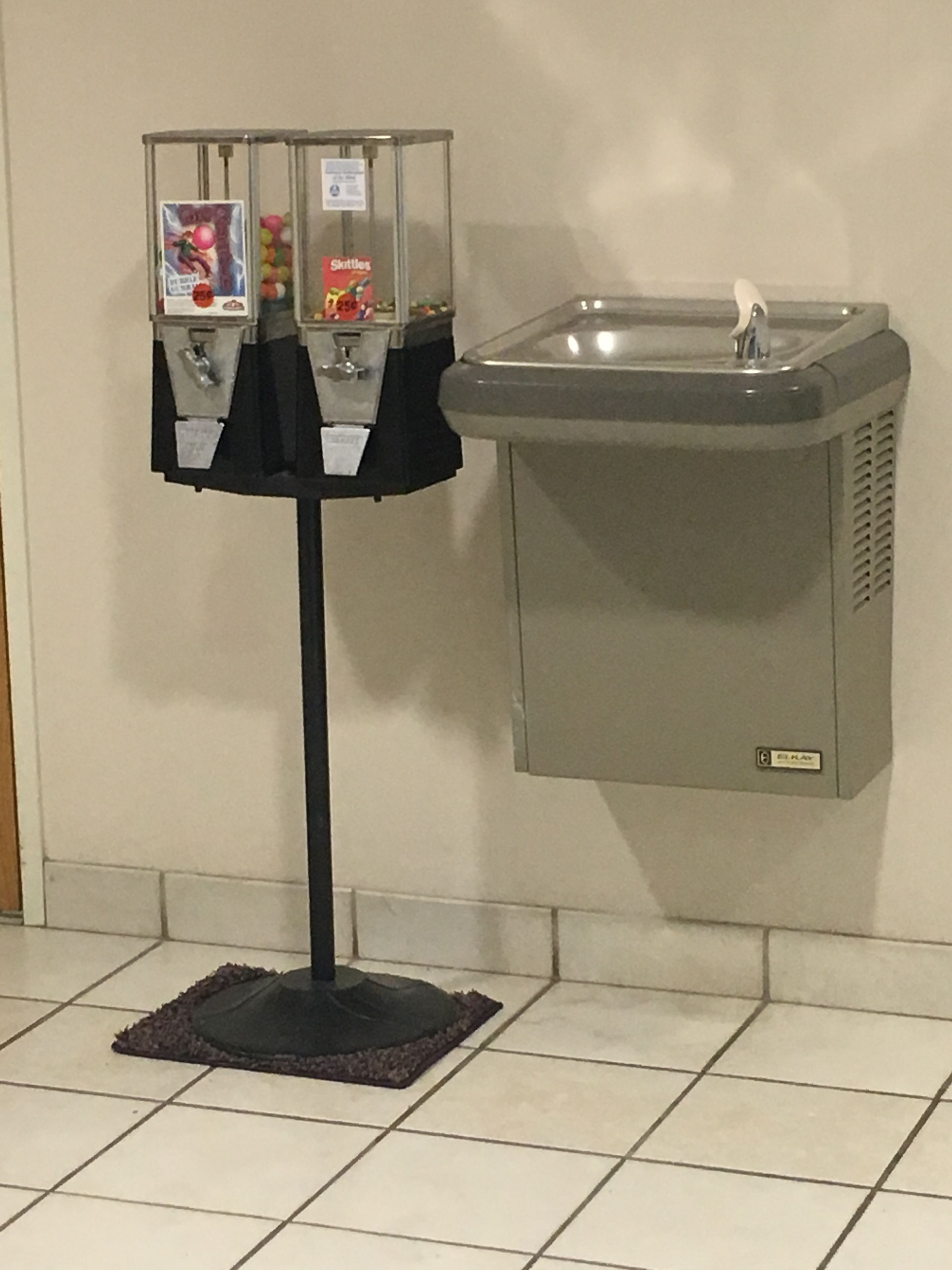 Un distributeur automatique de bonbons Skittles et un lavabo fixé au mur.