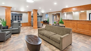 A lobby with a sofa, chairs, a coffee table, wooden accents, and a reception desk. - La Quinta Inn by Wyndham Missoula (Missoula)