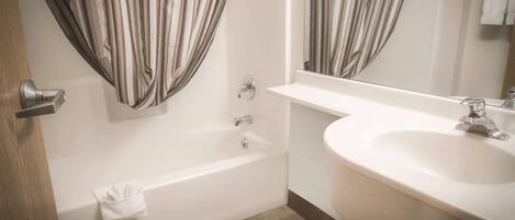 A bathroom with a bathtub, a sink, and a mirror.