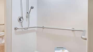 A bathroom with a shower, a grab bar, and a step stool with a towel.