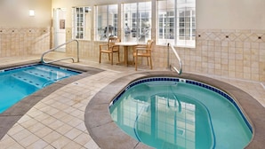 An indoor swimming pool with two separate sections, a seating area with chairs, and a window with a view of the outside. - La Quinta Inn by Wyndham Missoula (Missoula)