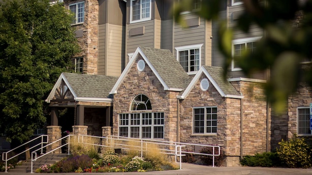 A multi-story building with stone and wood exterior, a covered entrance, and a landscaped front yard with stairs and railings. - La Quinta Inn by Wyndham Missoula (Missoula)