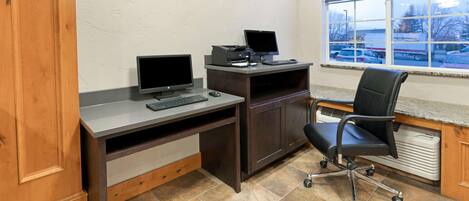 A home office with a desk, two monitors, a printer, and a chair.