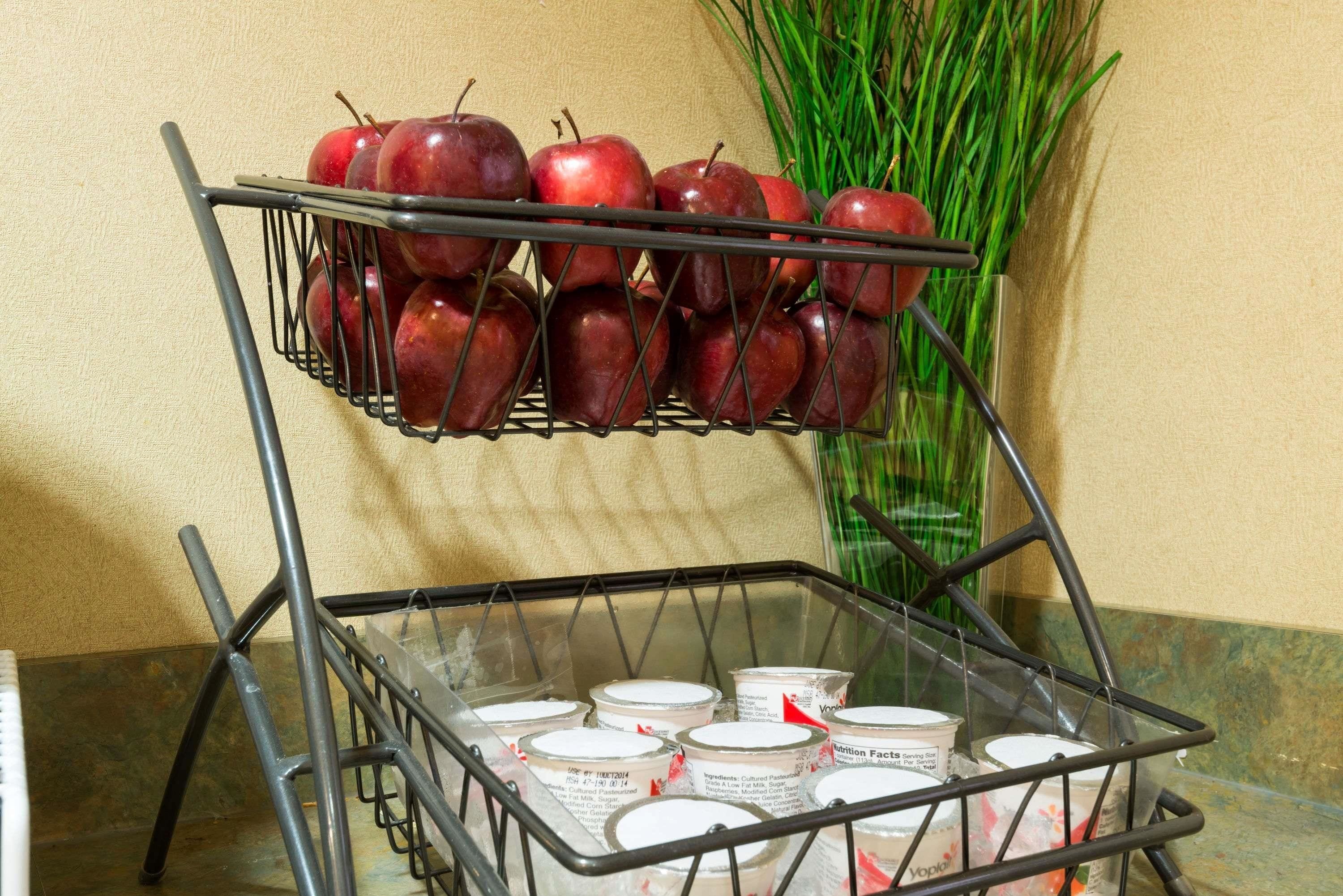 Una estructura metálica con manzanas y recipientes de yogur.