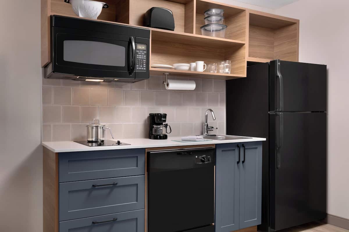 A modern kitchen with a black microwave, coffee maker, and refrigerator.