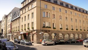 Un hotel a più piani con uno stile architettonico classico, caratterizzato da finestre ad arco e un tetto piatto.