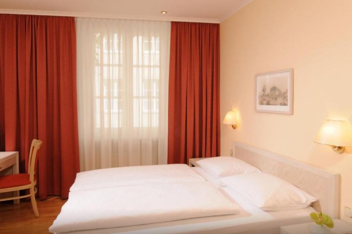 Een hotelkamer met twee bedden, een stoel, een bureau en een lamp.
