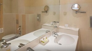 Een badkamer met twee wastafels, een toilet en een spiegel.