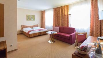 A hotel room with a bed, a sofa, a small table, and a TV.