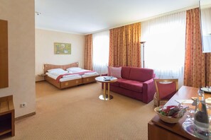 Une chambre d’hôtel avec un lit, un canapé, une petite table et un téléviseur.