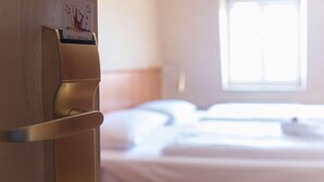 Une chambre d’hôtel équipée d’un lit, d’une table de chevet et d’une station de recharge fixée au mur.