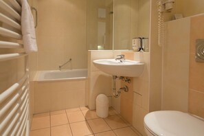 Et badeværelse med badekar, vask og toilet.