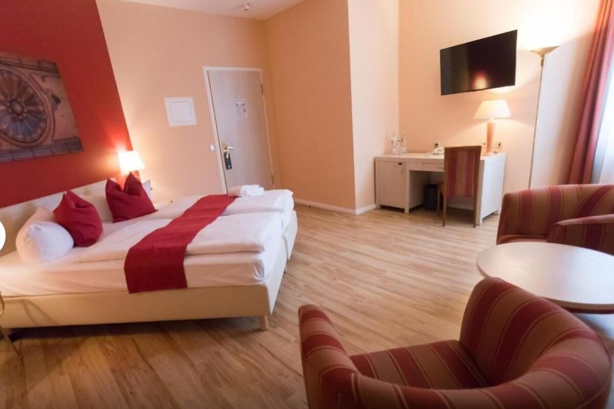 Een hotelkamer met een bed, een bureau, een stoel en een televisie.