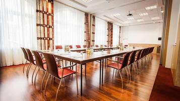 A conference room with a long table, red chairs, and a wooden floor.