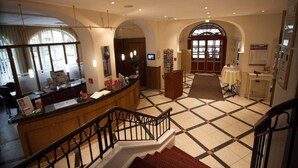 Una hall d'albergo con una reception, una scala e un pavimento piastrellato.