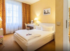 A hotel room with a bed, a desk, a chair, and a window with curtains. - Martas Hotel Albrechtshof Berlin (Berlin)