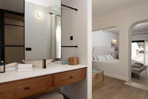 A modern bathroom with a large mirror, white vanity, and a wooden bench.