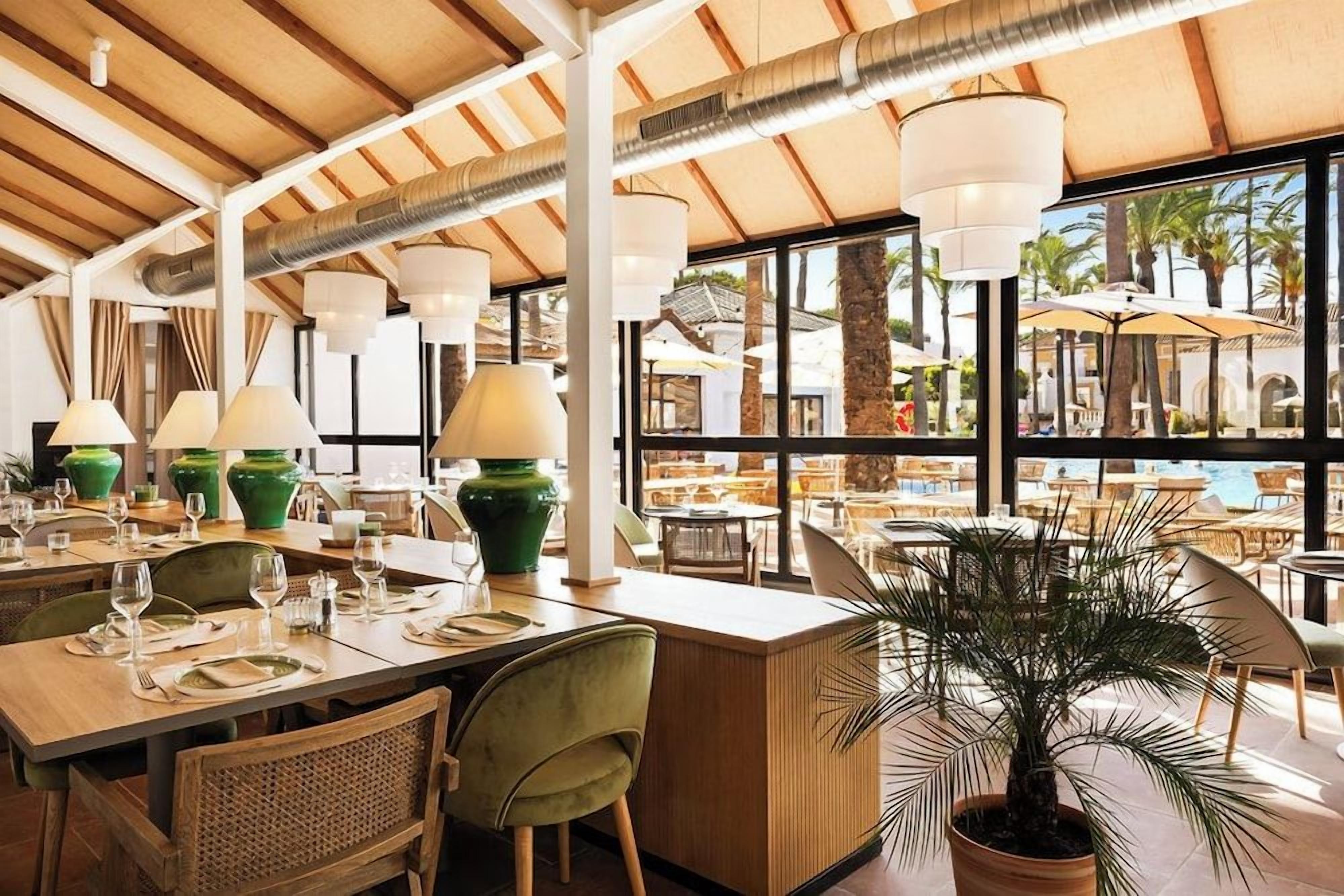 A restaurant with tables set for dining, a bar area, and a view of the outdoors.