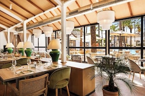 A restaurant with tables set for dining, a bar area, and a view of the outdoors. - Hotel San Roque (San Roque)