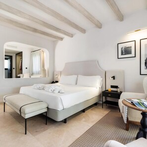 A modern bedroom with a large bed, a bedside table, a chair, and a mirror. - Hotel San Roque (San Roque)