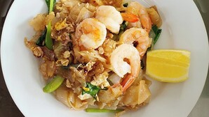 A plate of Pad Thai with shrimp and a lemon wedge. - Posthouse MotorLodge (Goulburn)