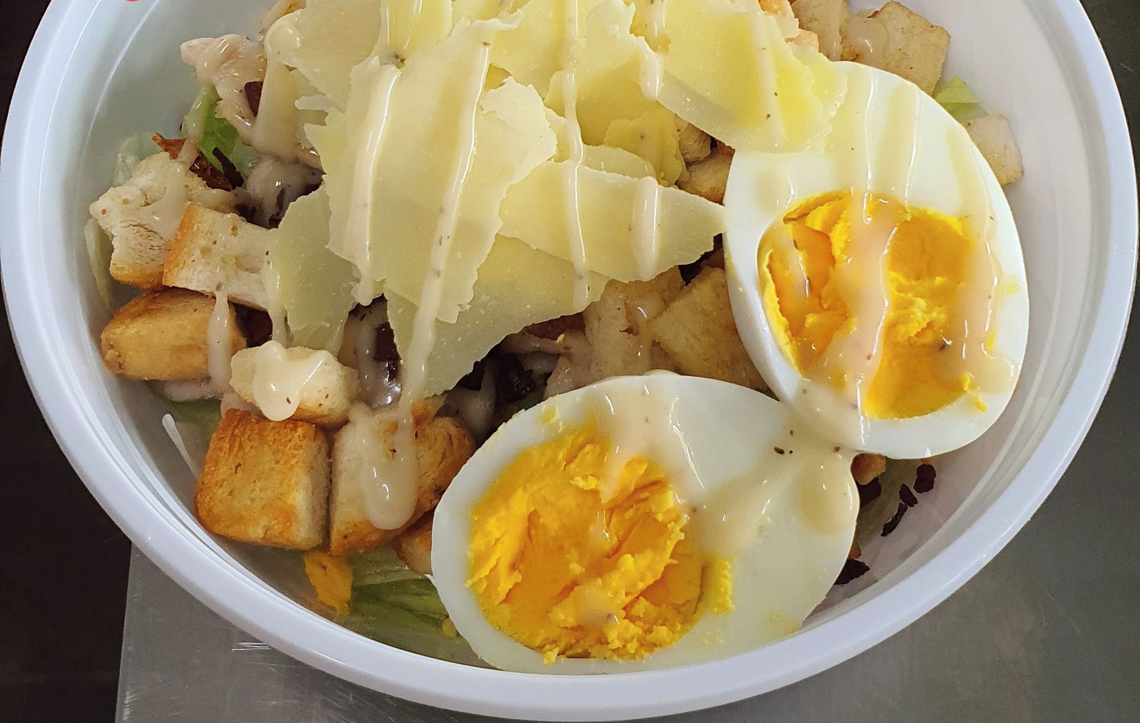 Salada Caesar com croutons, queijo ralado e ovos cozidos ao meio.