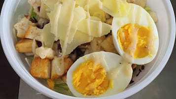 Salada Caesar com croutons, queijo ralado e ovos cozidos ao meio.