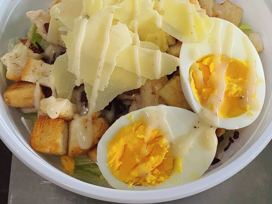 Salada Caesar com croutons, queijo ralado e ovos cozidos ao meio.
