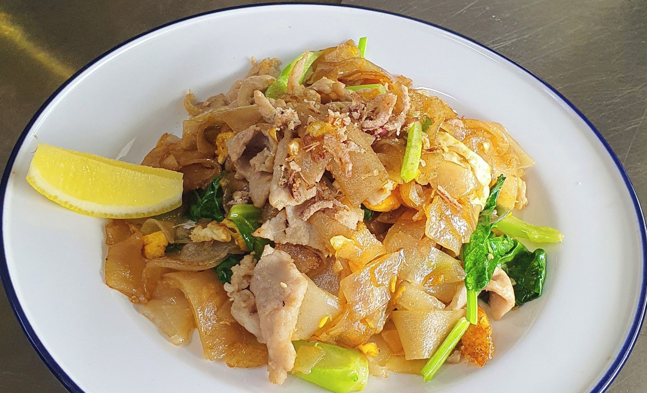 A plate of Pad Thai with a slice of lemon on the side.