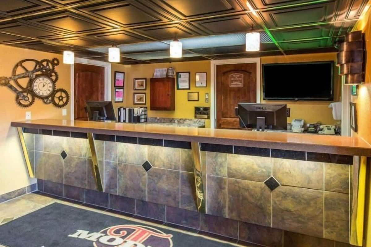 A hotel reception area with a counter, a clock, framed pictures, and a television.