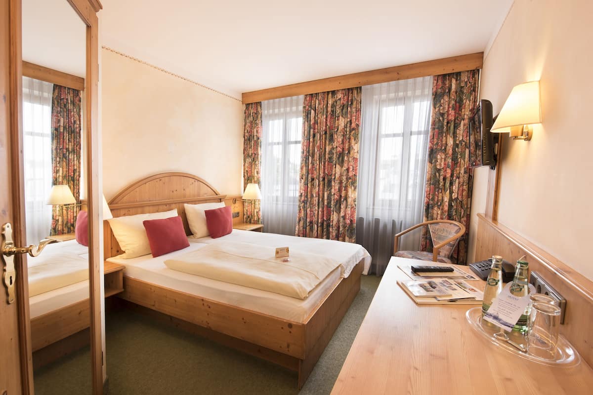 Une chambre d’hôtel avec un lit en bois, un bureau avec une lampe et une chaise.