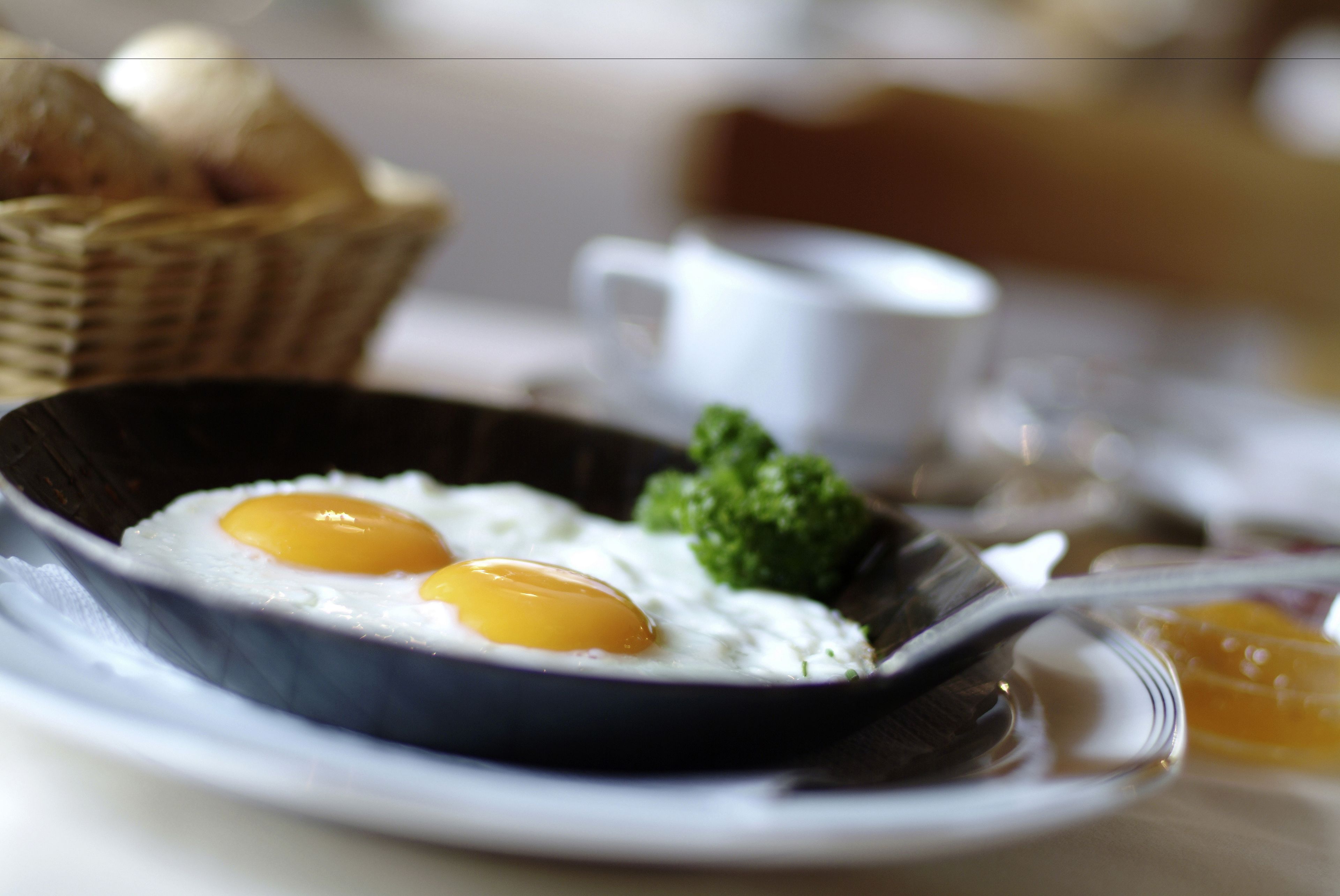 A breakfast setting with eggs in a bowl, a cup, and a basket in the background.